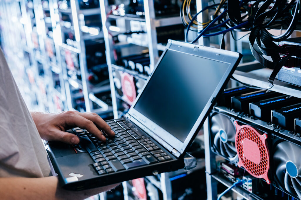 Mann mit Laptop im Serverraum